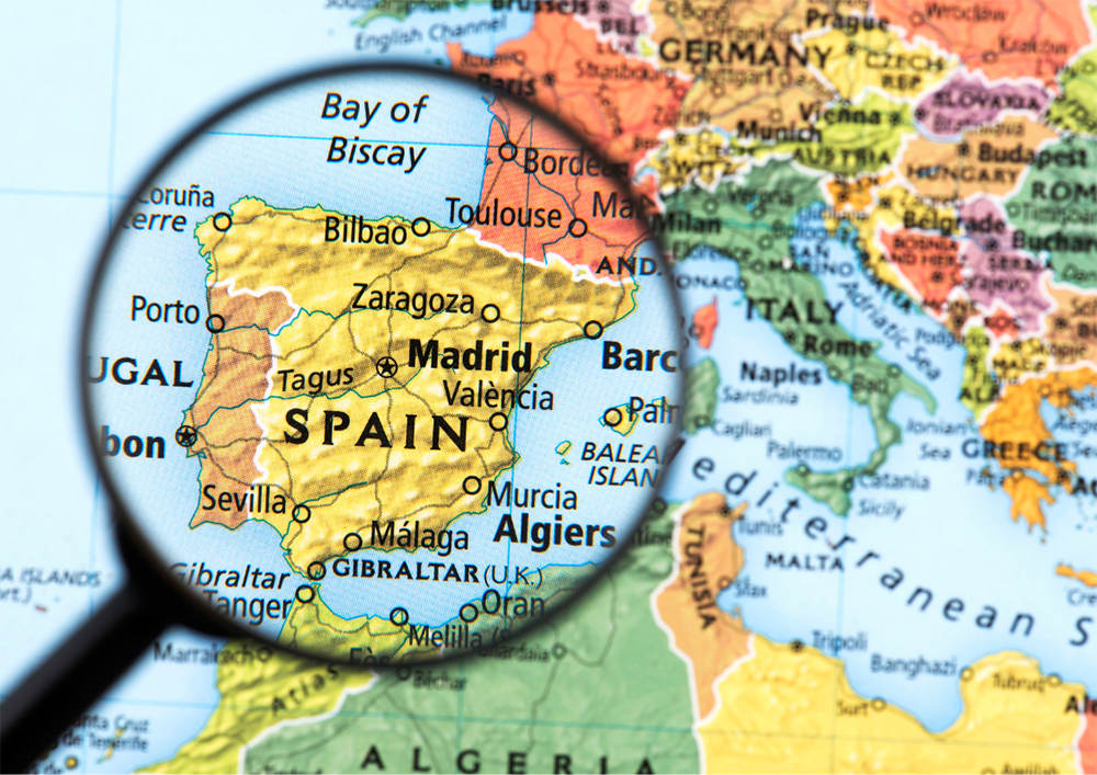 Un mapa de España con una lupa encima.
