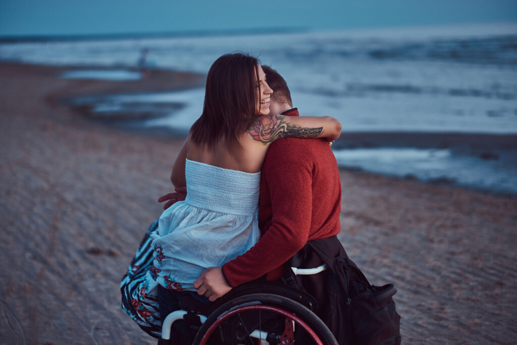 Pareja disfrutando de la playa durante un viaje, con una persona usuaria de silla de ruedas.