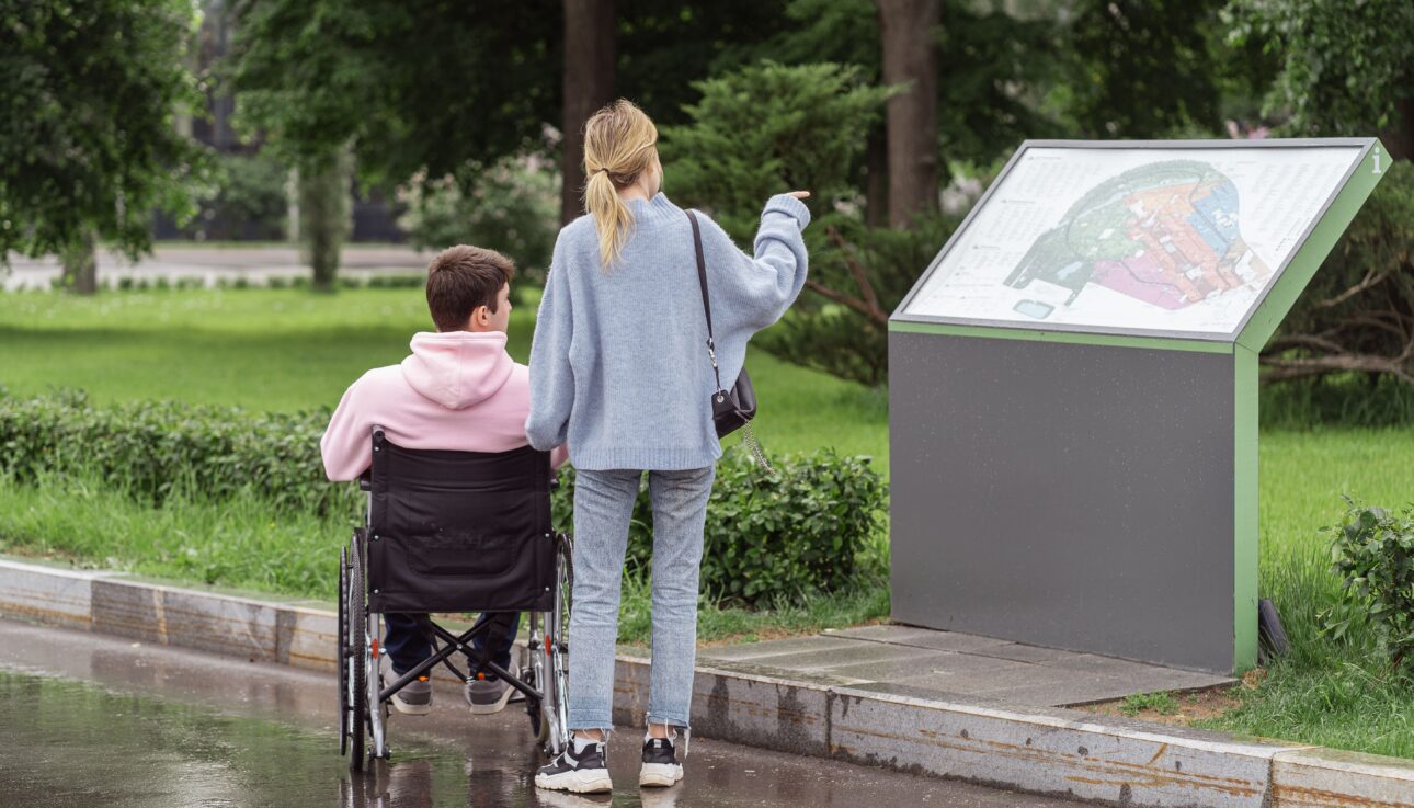 Pareja consultando un mapa durante un viaje, con una persona usuaria de silla de ruedas.