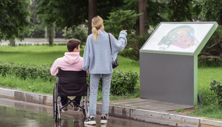 Pareja consultando un mapa durante un viaje, con una persona usuaria de silla de ruedas.